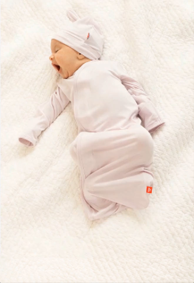 Baby wearing a hat & gown set. Button leads to the Gowns & Take Me Home Sets collection page.