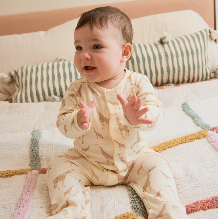 Baby wearing a footie made from Organic Cotton with the Jolie Giraffe print.
