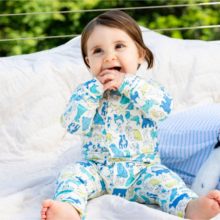 Baby wearing a convertible cover made from the RightFit™ fabric with the It's A Paw-ty Blue print.