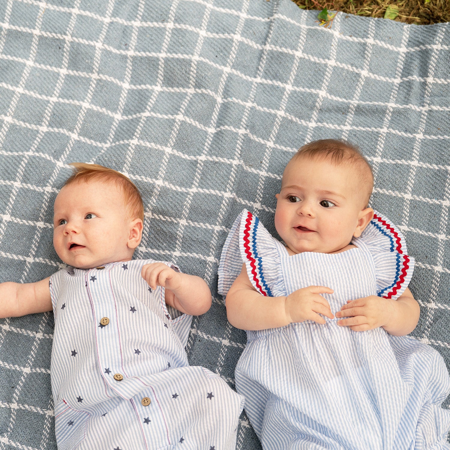 Two babies lying on a checkered blanket outdoors by Magnetic Me.