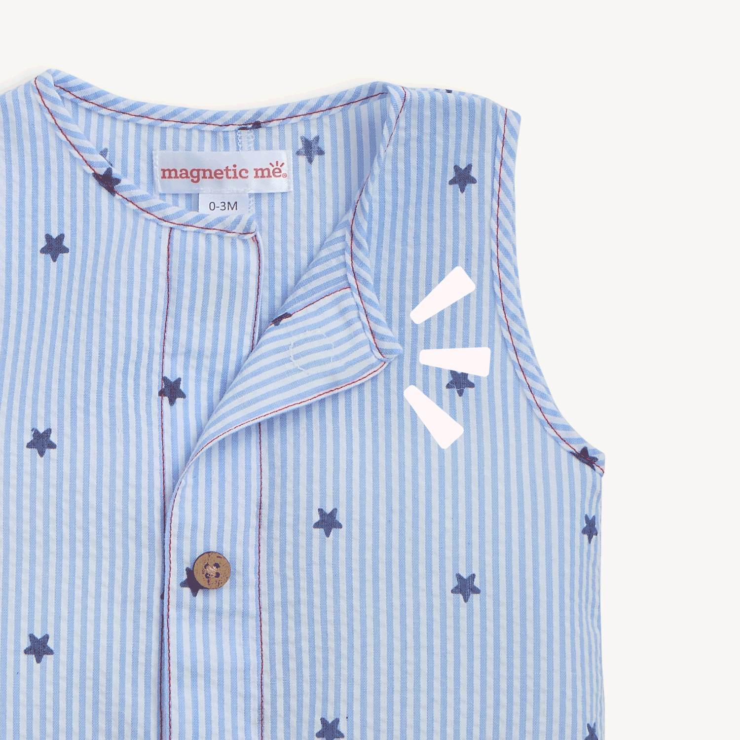 Open and close movement of the magnet on the top of A light blue and white striped seersucker sleeveless romper featuring navy star print, wood-look buttons, and front pockets, by Magnetic Me.