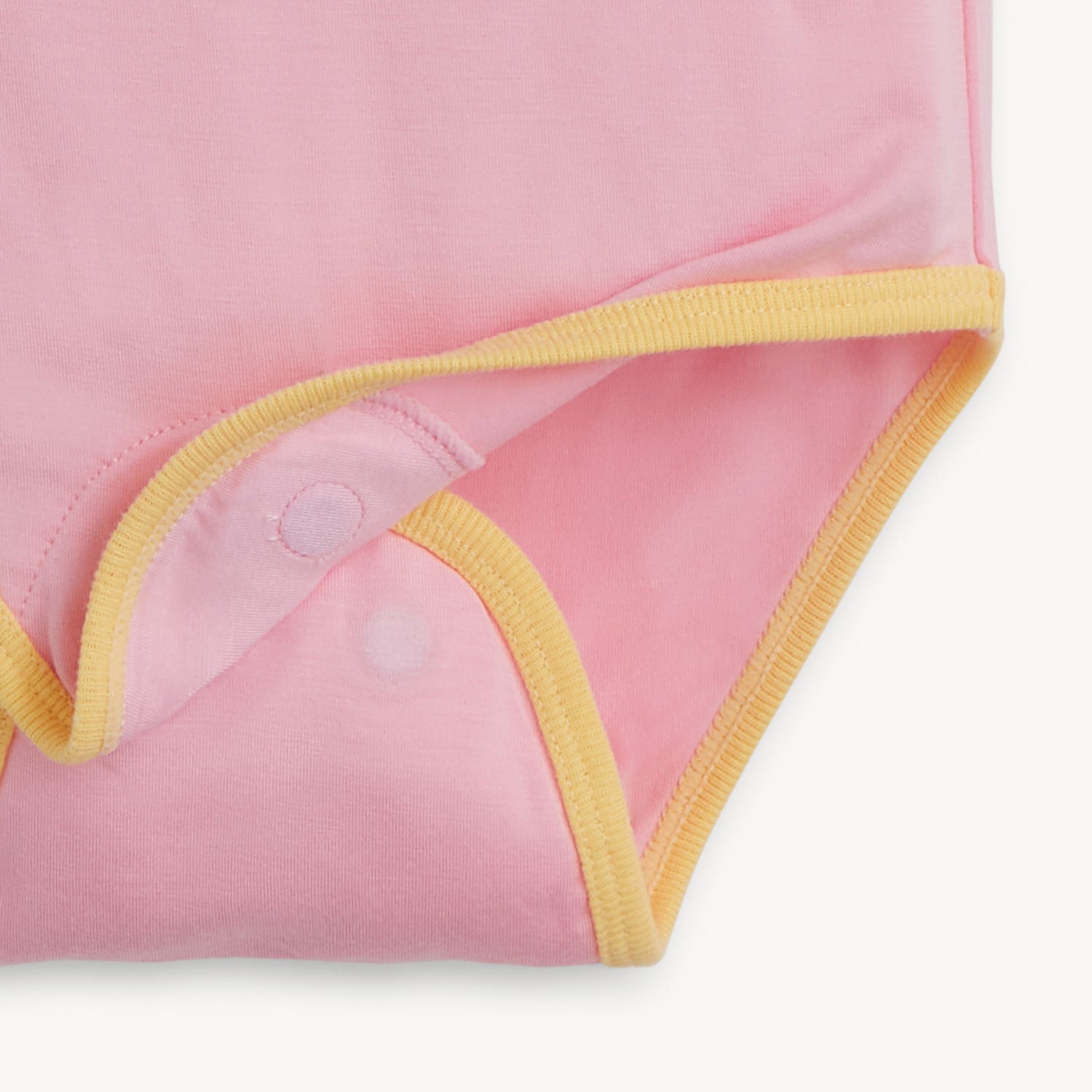 Open magnet on the bottom of a pink short-sleeve bodysuit with yellow trim, by Magnetic Me.