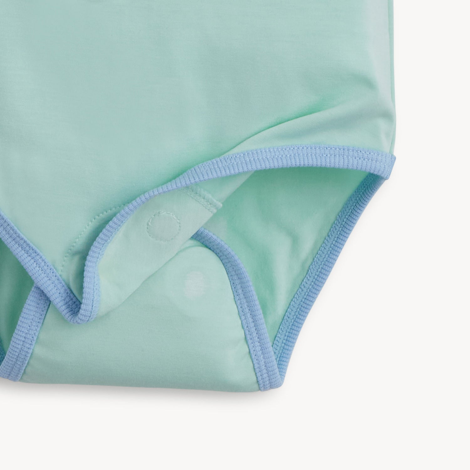 Open magnet on the bottom of the a light green short-sleeve bodysuit with blue trim, by Magnetic Me.