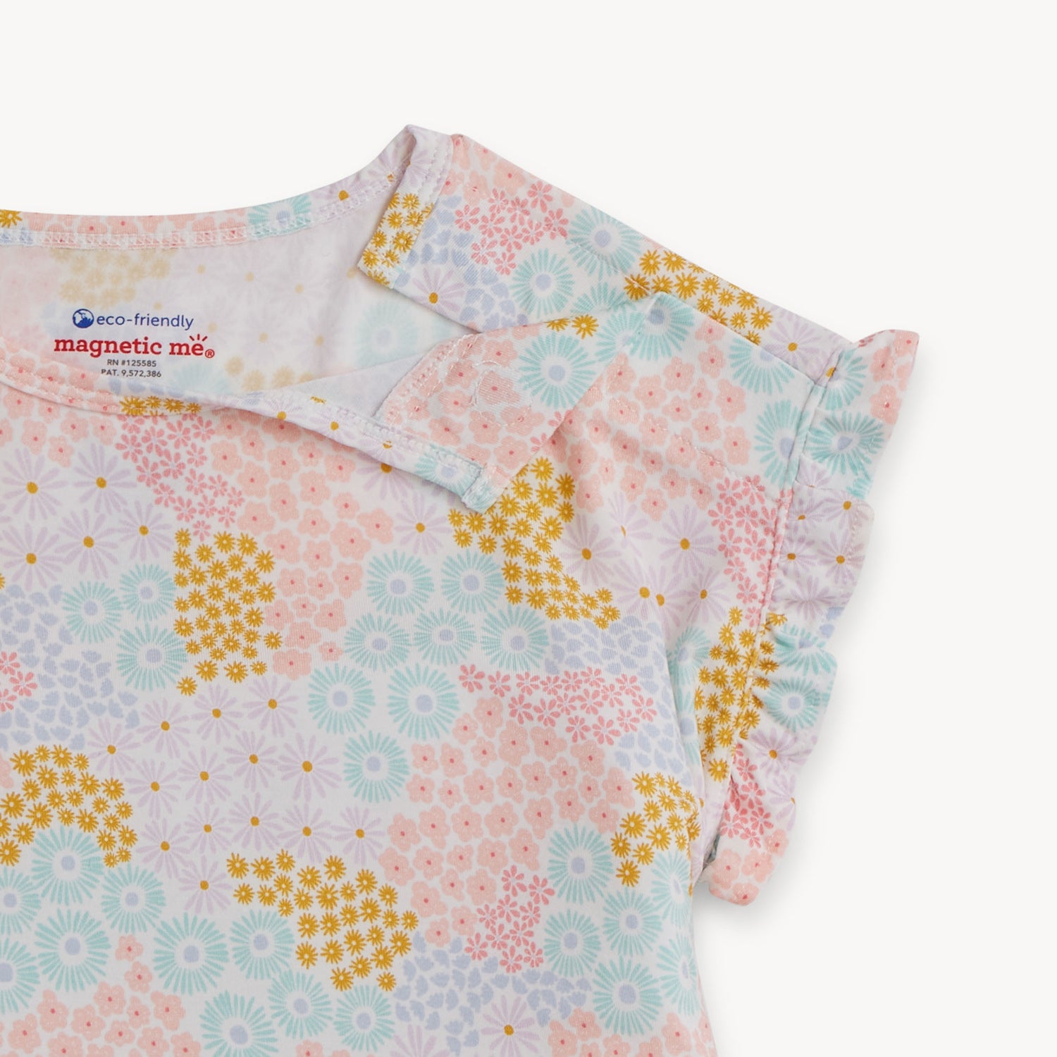 Open magnet in the shoulder area of A child short set including a ruffle-sleeve top and matching ruffled shorts in a colorful pastel floral print with pink and gold accents, by Magnetic Me.