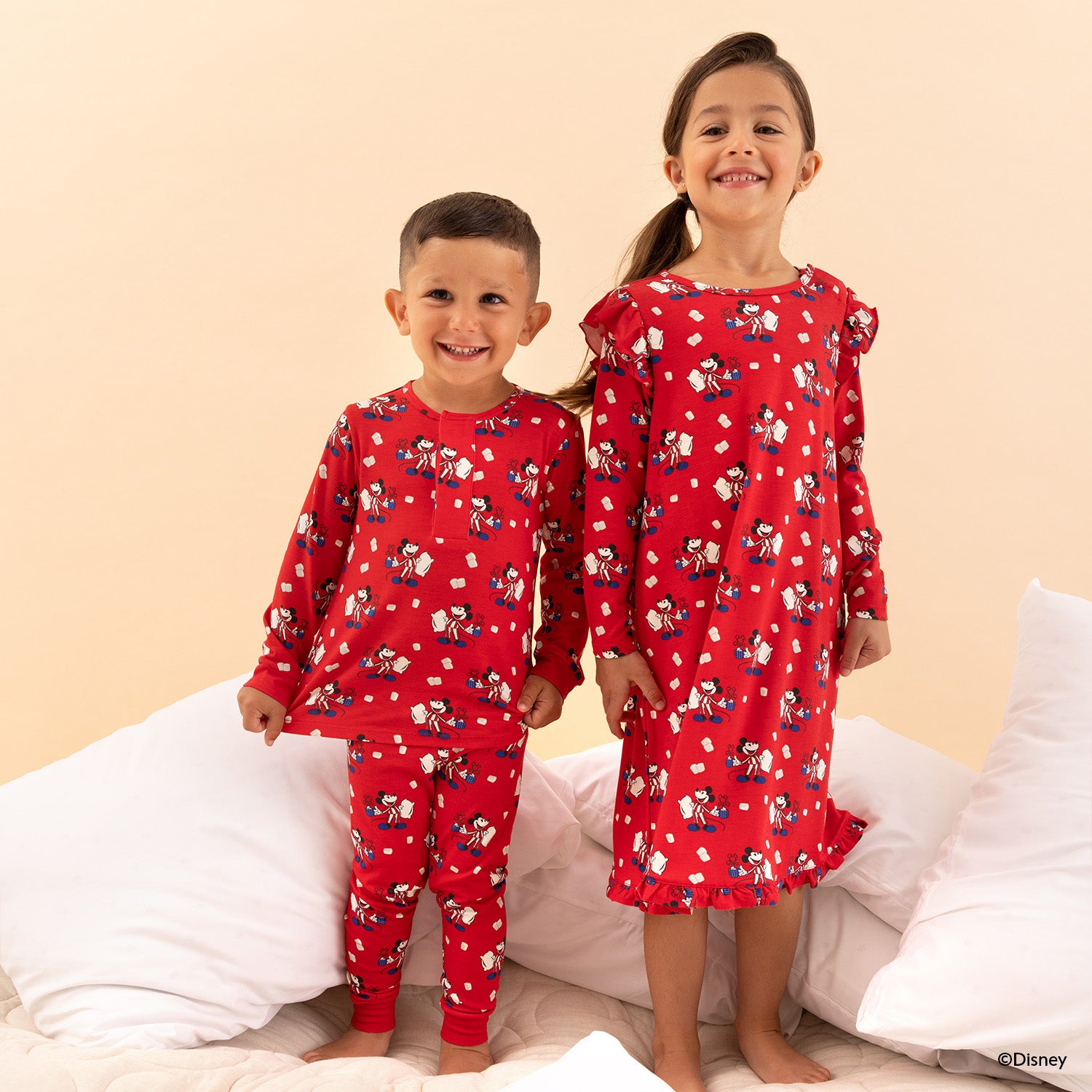 Two children wearing red pajamas with cartoon characters on a beige background