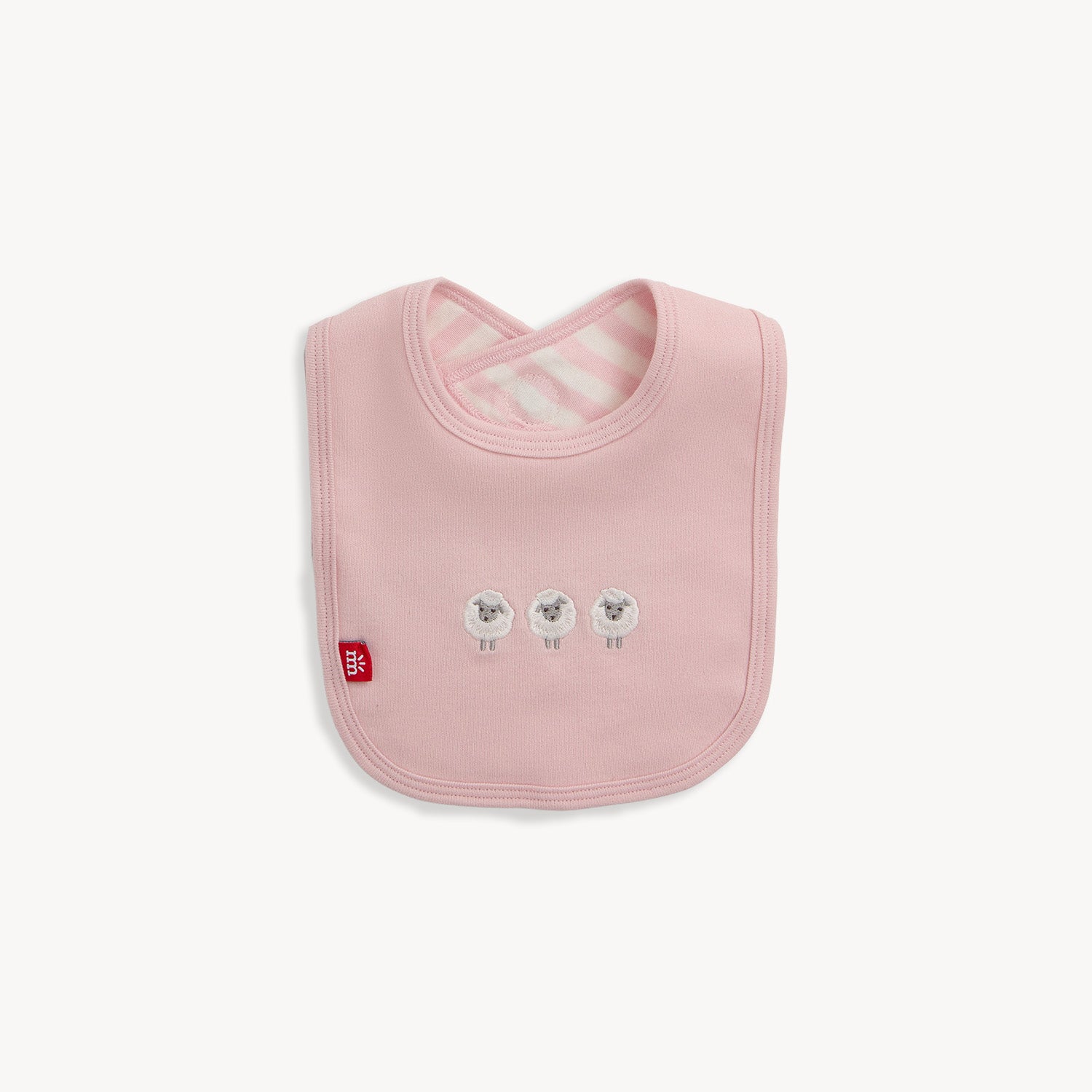 A reversible bib with slate pink and white stripes on one side and a solid slate pink side featuring three embroidered white sheep, by Magnetic Me.