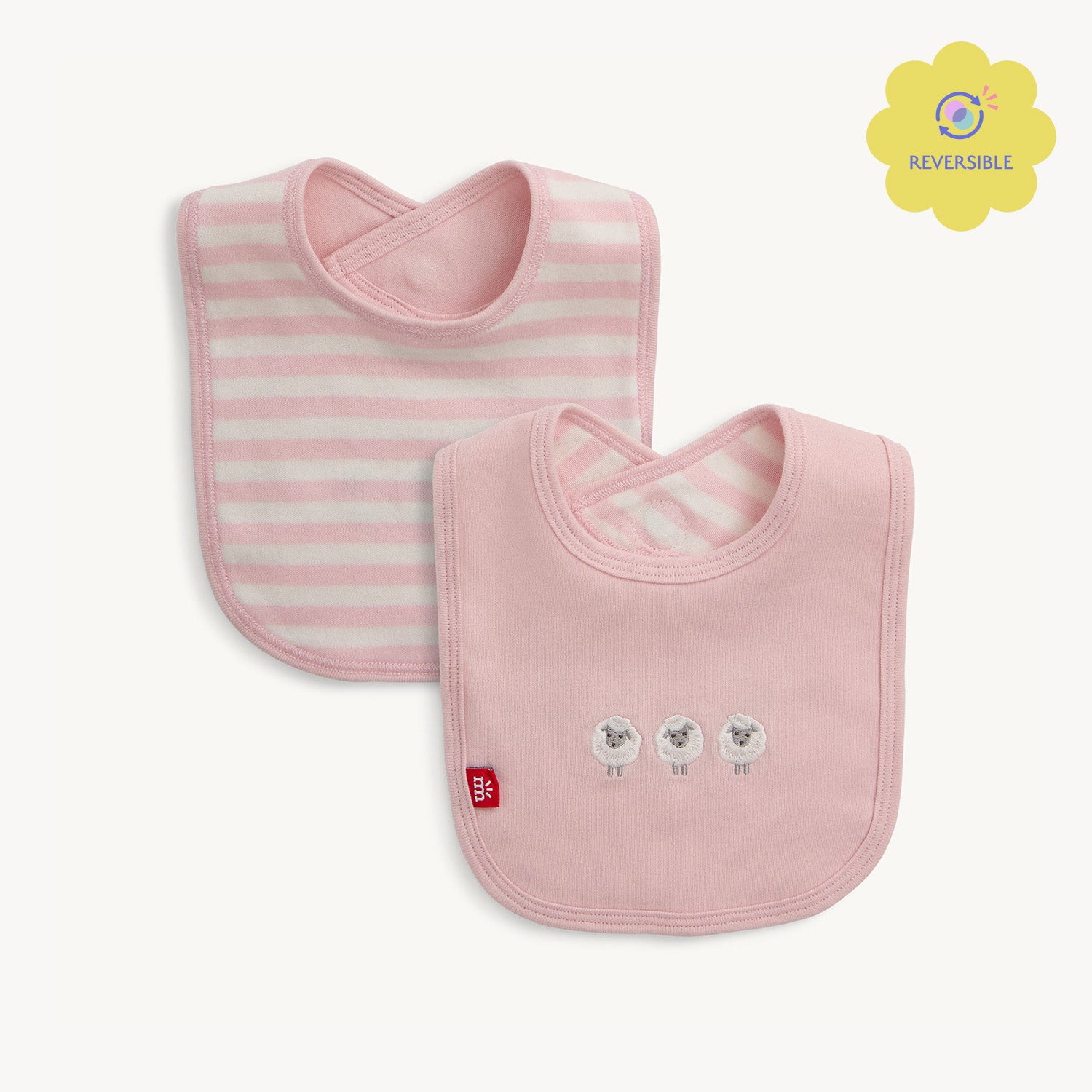 A reversible bib with slate pink and white stripes on one side and a solid slate pink side featuring three embroidered white sheep, by Magnetic Me.