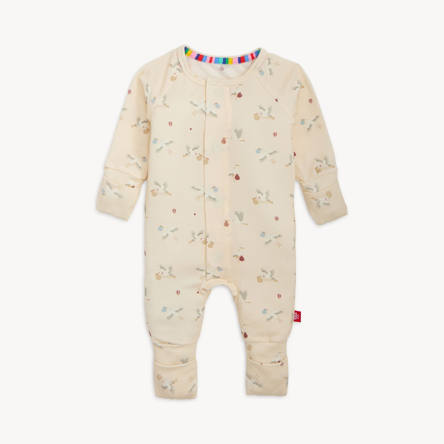 cream-colored long-sleeve convertible coverall with a repeating pattern of storks and hot air balloons, by Magnetic Me.