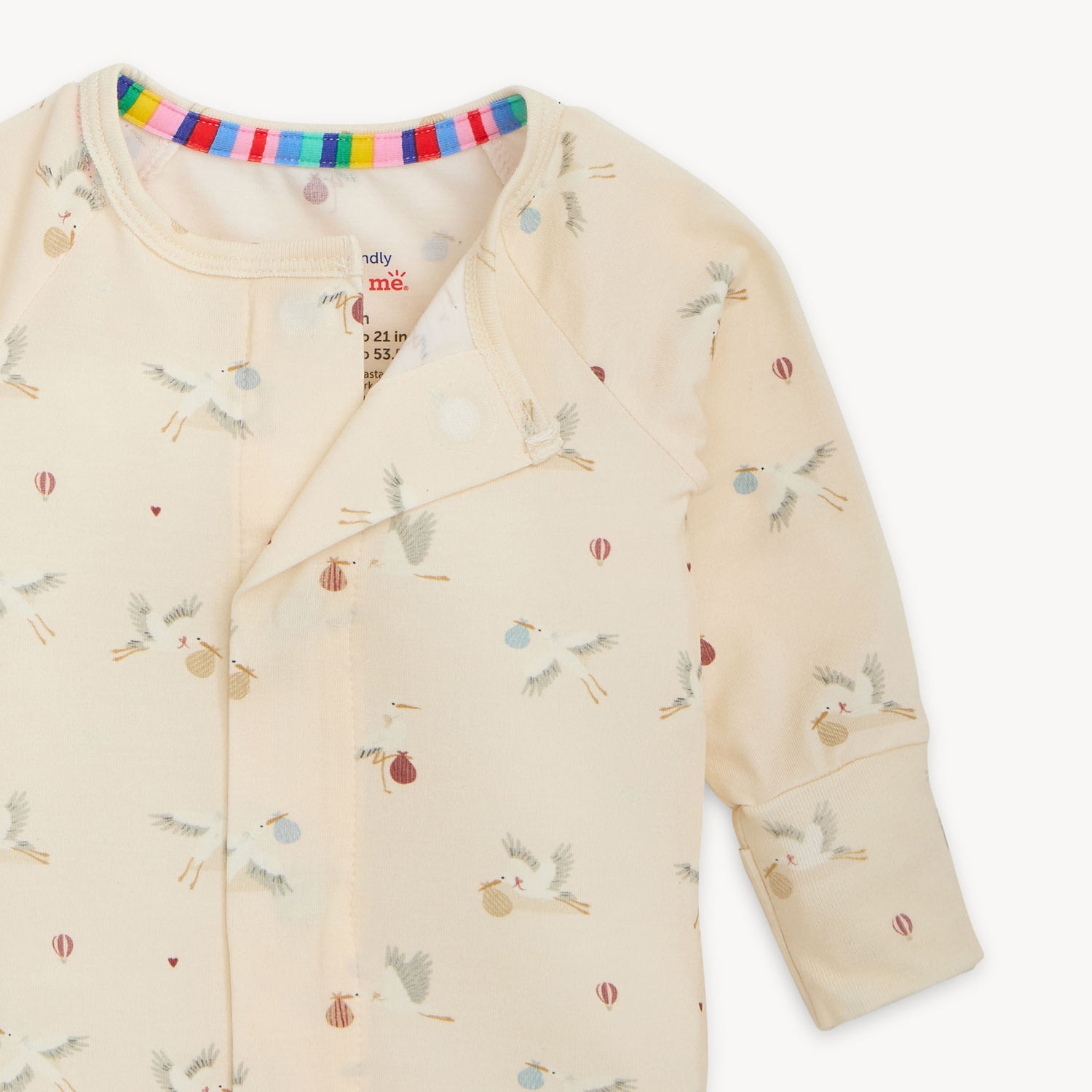 Open magnet of A cream-colored long-sleeve convertible coverall with a repeating pattern of storks and hot air balloons, by Magnetic Me.