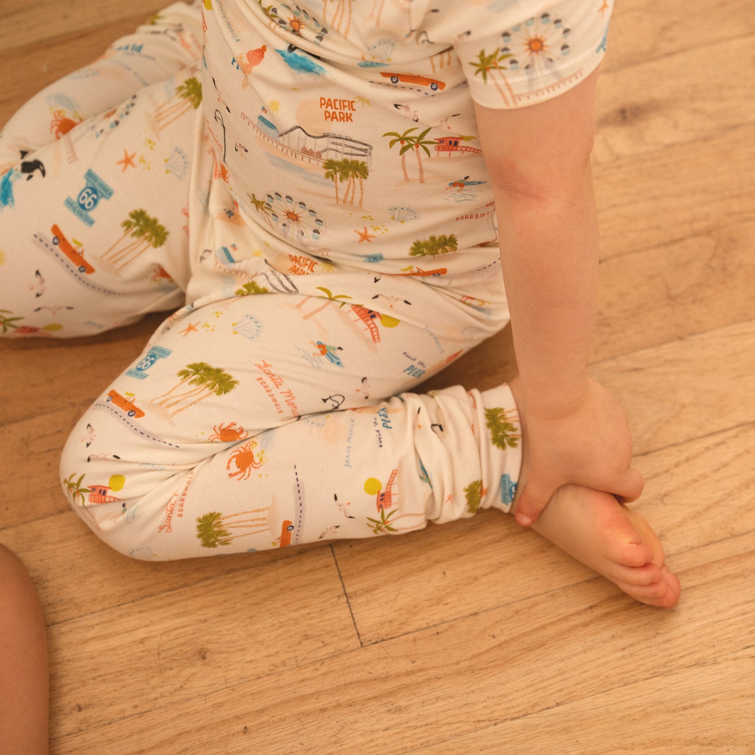 Child's legs wearing patterned pants on a wooden floor