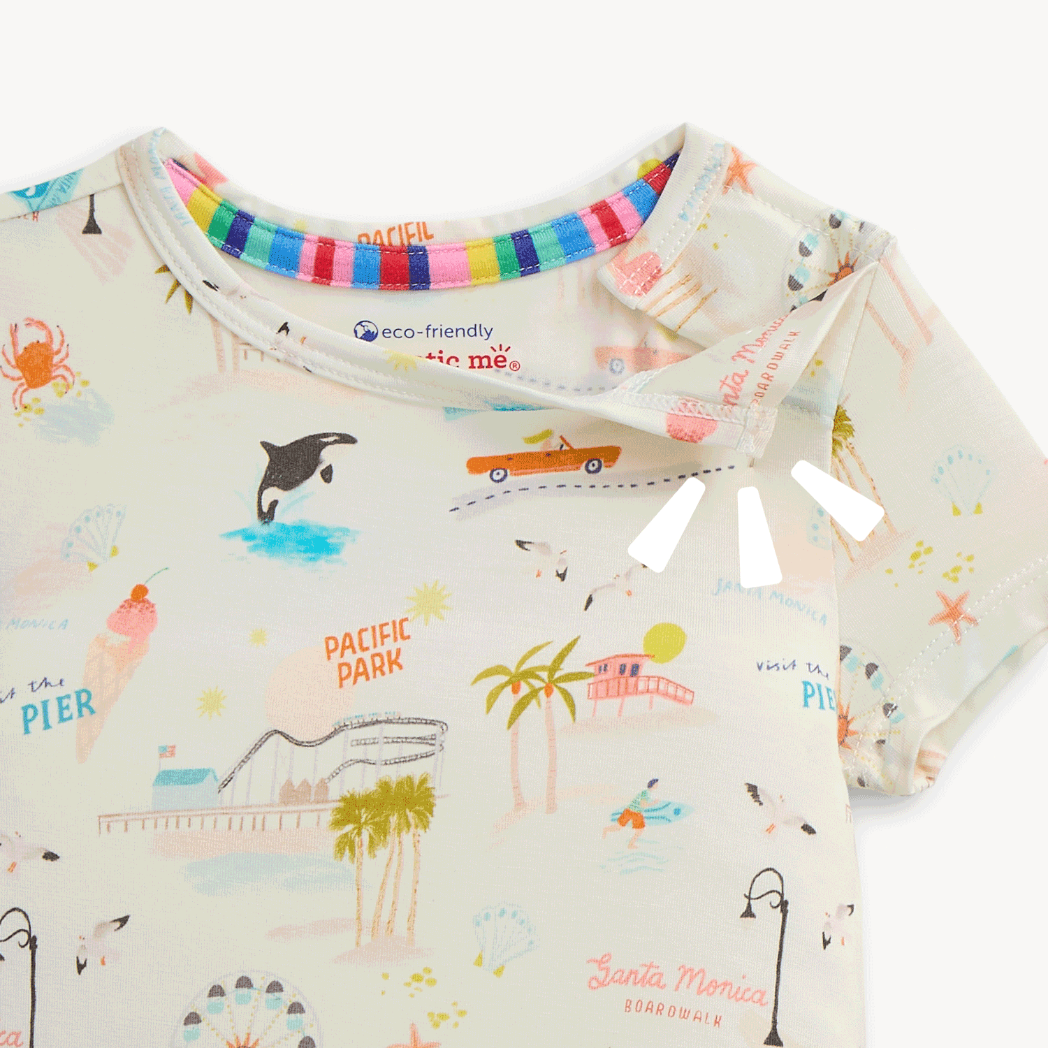 Open and closing magnet on the shoulder of A baby and child sleepwear set includes a short sleeve top and matching long pants adorned with the detailed Santa Monica coastline and amusement park print by Magnetic Me.