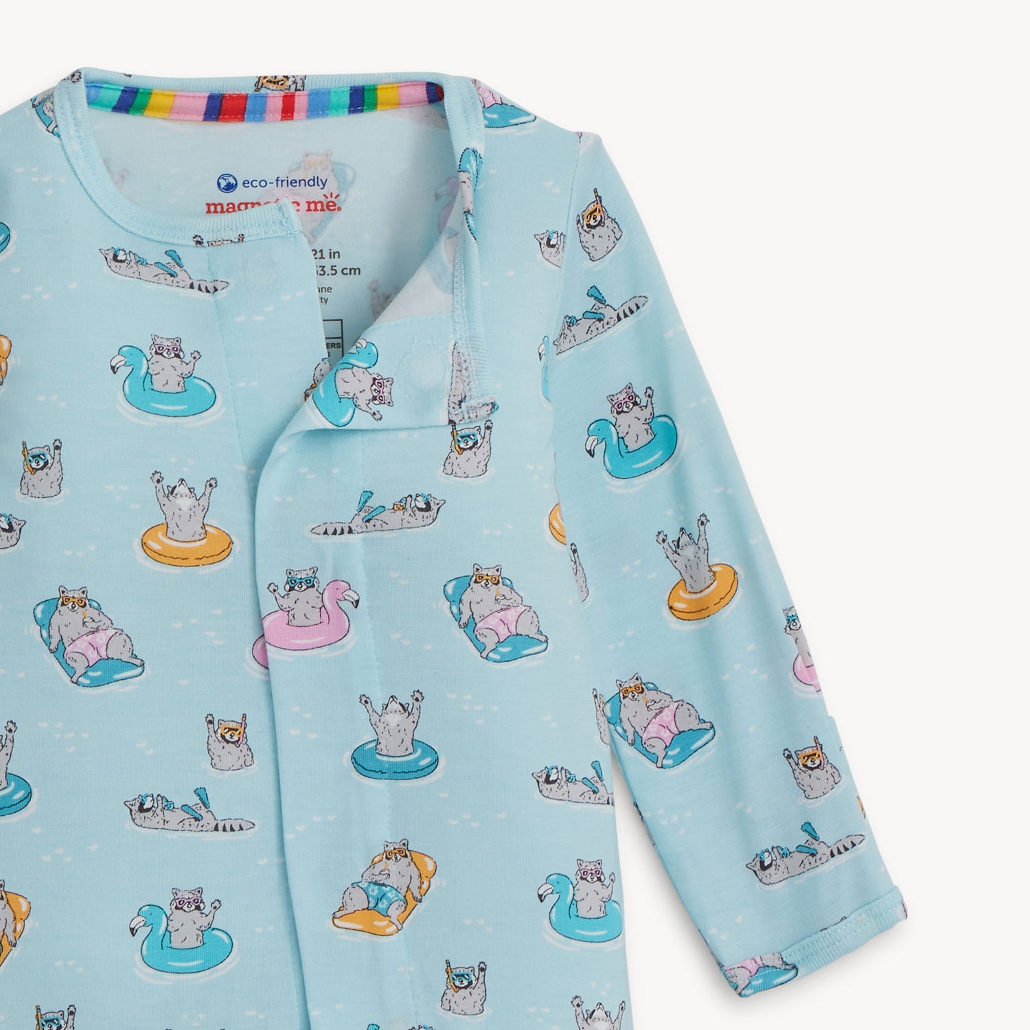 Open magnet in the center front of A long-sleeve light blue footie featuring a playful print of raccoons lounging on colorful pool floats and snorkeling, by Magnetic Me.