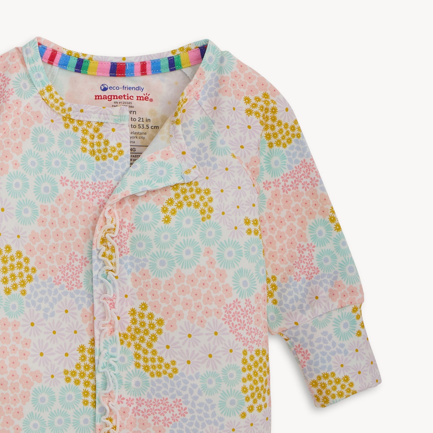 Open magnet in the front center of A long-sleeve convertible coverall with ruffle detailing and a multi-colored pastel floral pattern, by Magnetic Me.