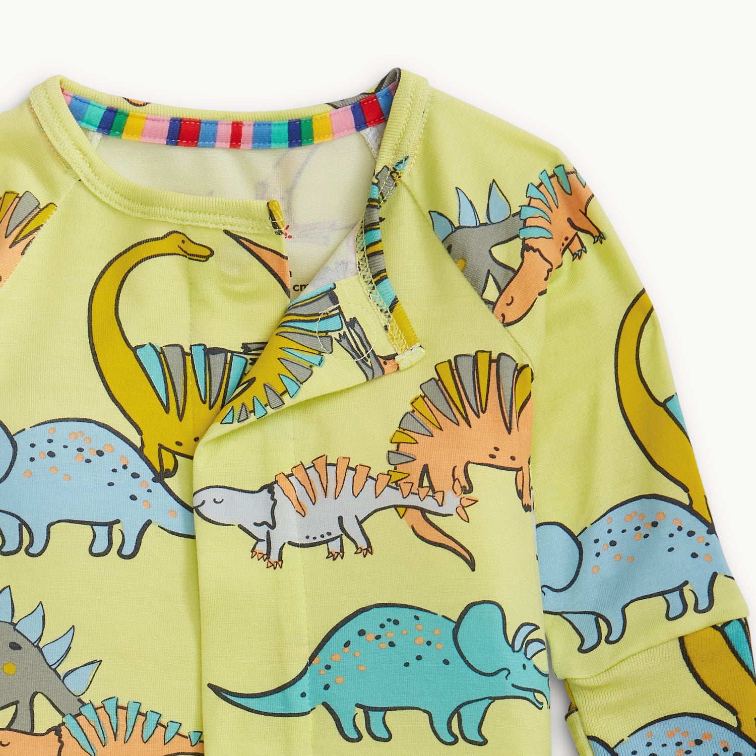 Open magnet in the front center of A lime green long-sleeve convertible coverall with a playful multi-colored dinosaur pattern and ribbed cuffs, by Magnetic Me.
