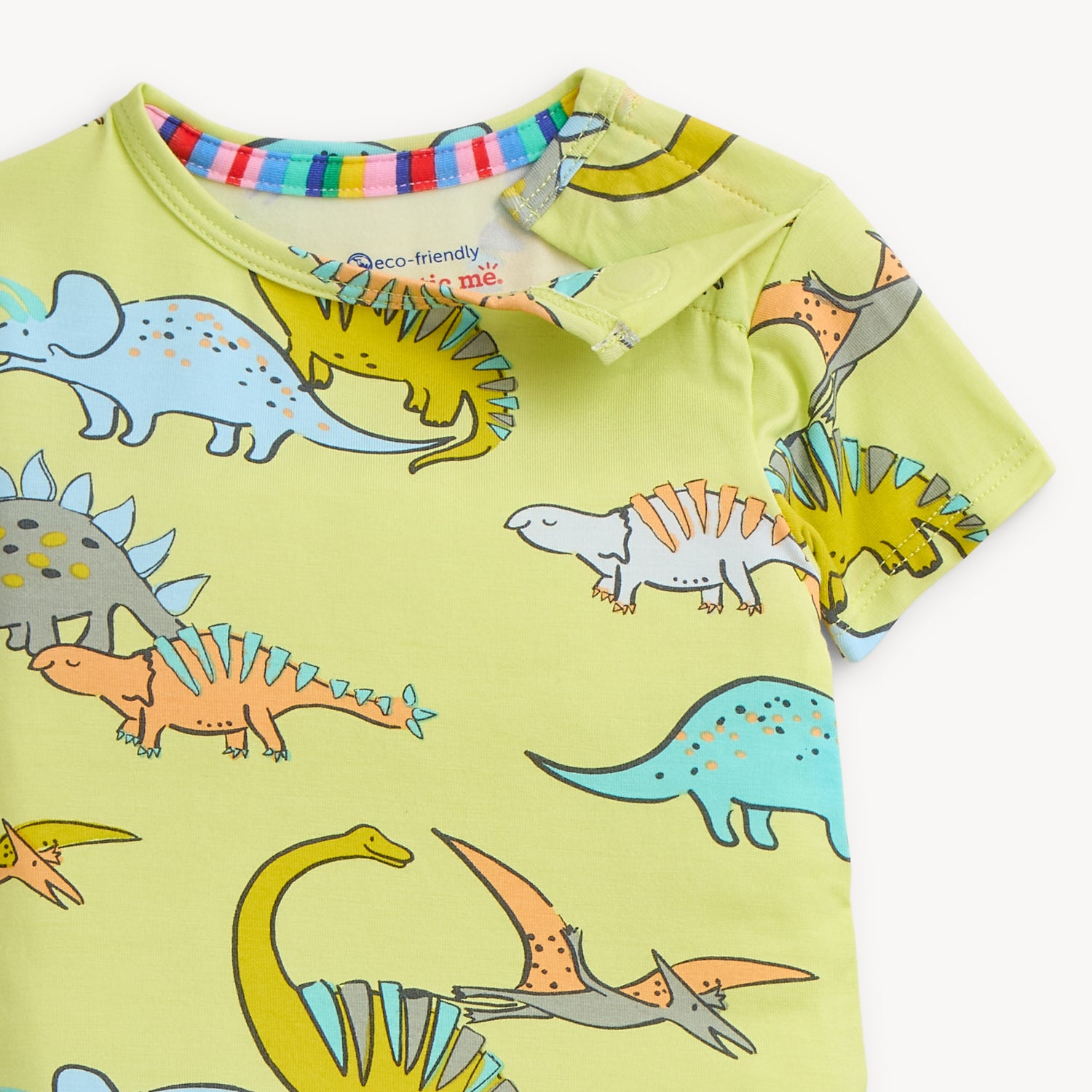 Open magnet on the shoulder area of A two-piece pajama set with a short-sleeve top and long pants in lime green fabric covered in a whimsical dinosaur print, by Magnetic Me.