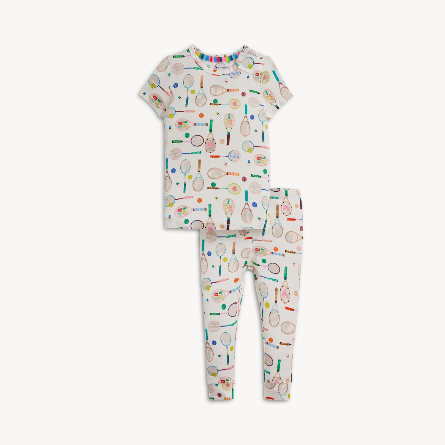 A two-piece pajama set with a cream short-sleeve top and long pants covered in a whimsical tennis and badminton equipment print, by Magnetic Me.