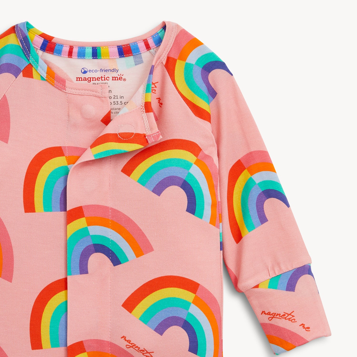 Open magnet in the center front of A pink long-sleeve convertible coverall decorated with a colorful all-over rainbow print and ribbed cuffs, by Magnetic Me.