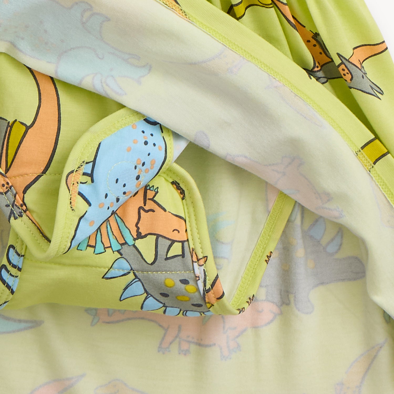Close-up of a integrated bodysuit featuring a colorful dinosaur pattern, by Magnetic Me.