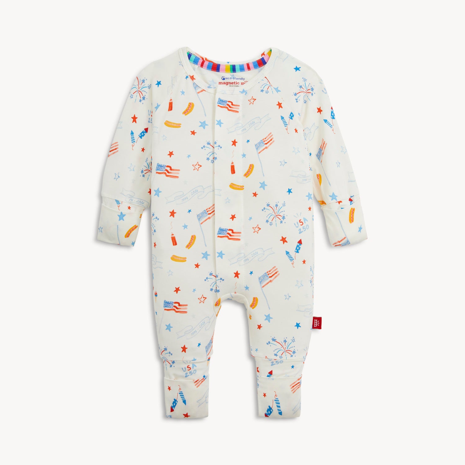 A white long-sleeve convertible coverall decorated with a festive repeating print of stars, banners, and picnic foods, by Magnetic Me.