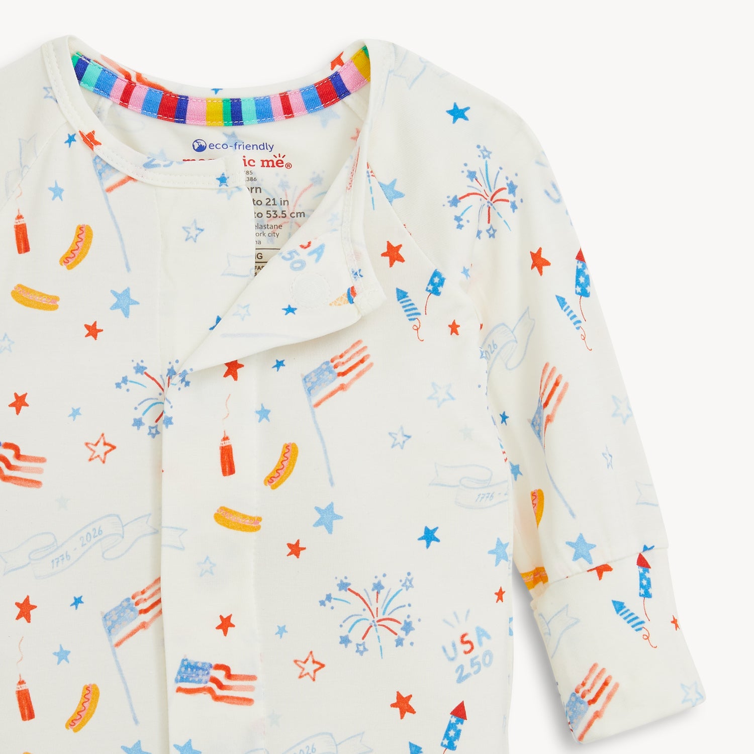 Open magnet in the center front of A white long-sleeve convertible coverall decorated with a festive repeating print of stars, banners, and picnic foods, by Magnetic Me.