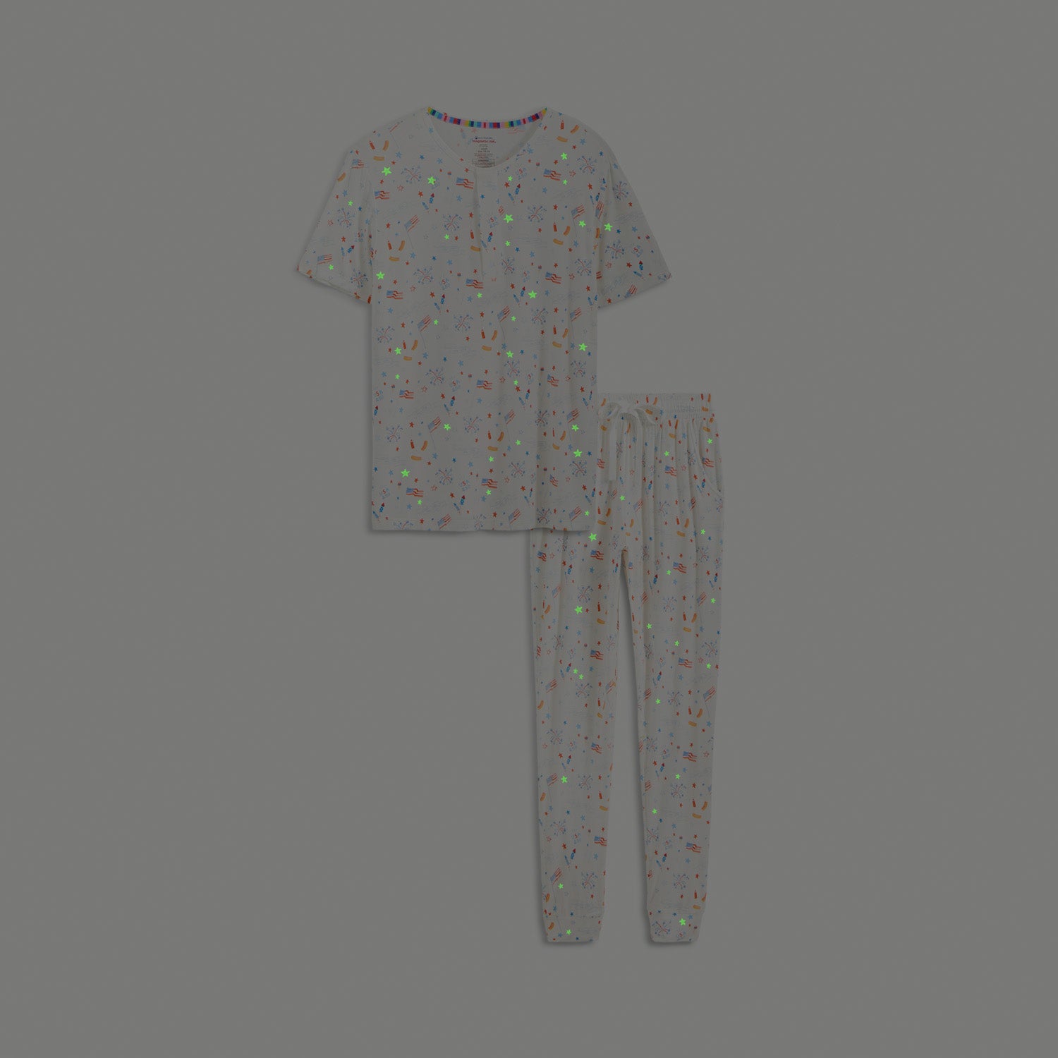 Glow in the dark men's two-piece pajama set including a button-neck short-sleeve top and jogger-style pants in a festive white Fourth of July themed print, by Magnetic Me.