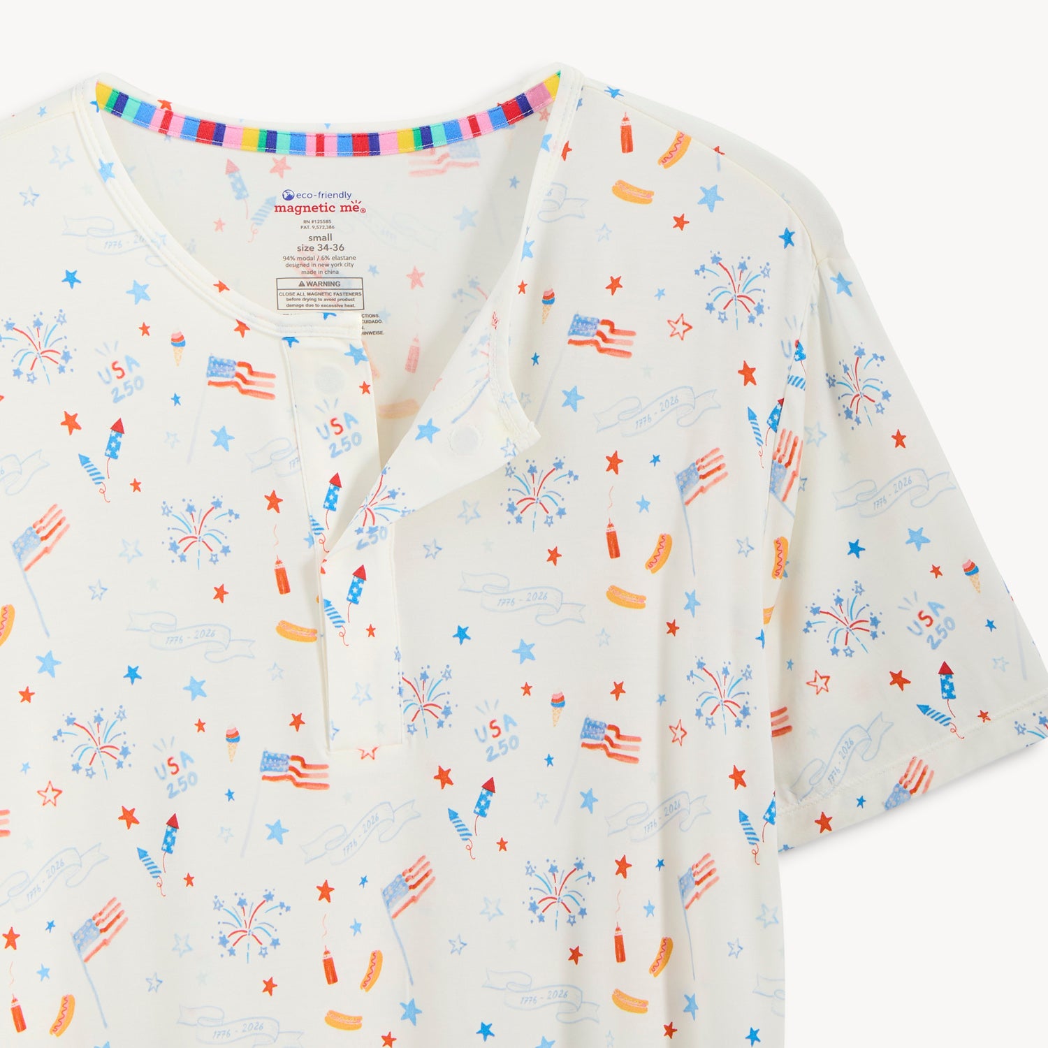 Open magnet in the front center of A men's two-piece pajama set including a button-neck short-sleeve top and jogger-style pants in a festive white Fourth of July themed print, by Magnetic Me.