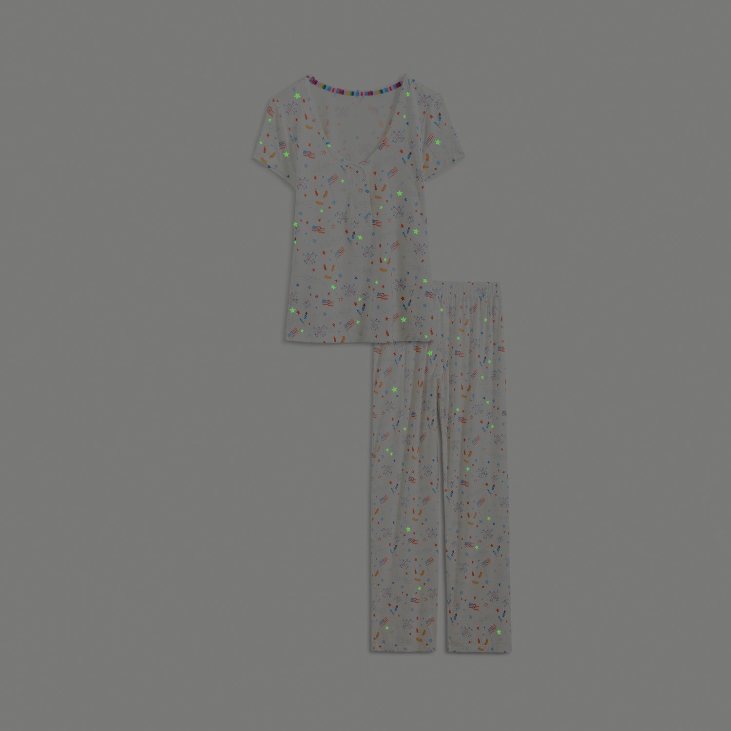 Glow in the dark women's two-piece set featuring a V-neck short-sleeve top and long pants in white fabric with an all-over patriotic holiday print, by Magnetic Me.