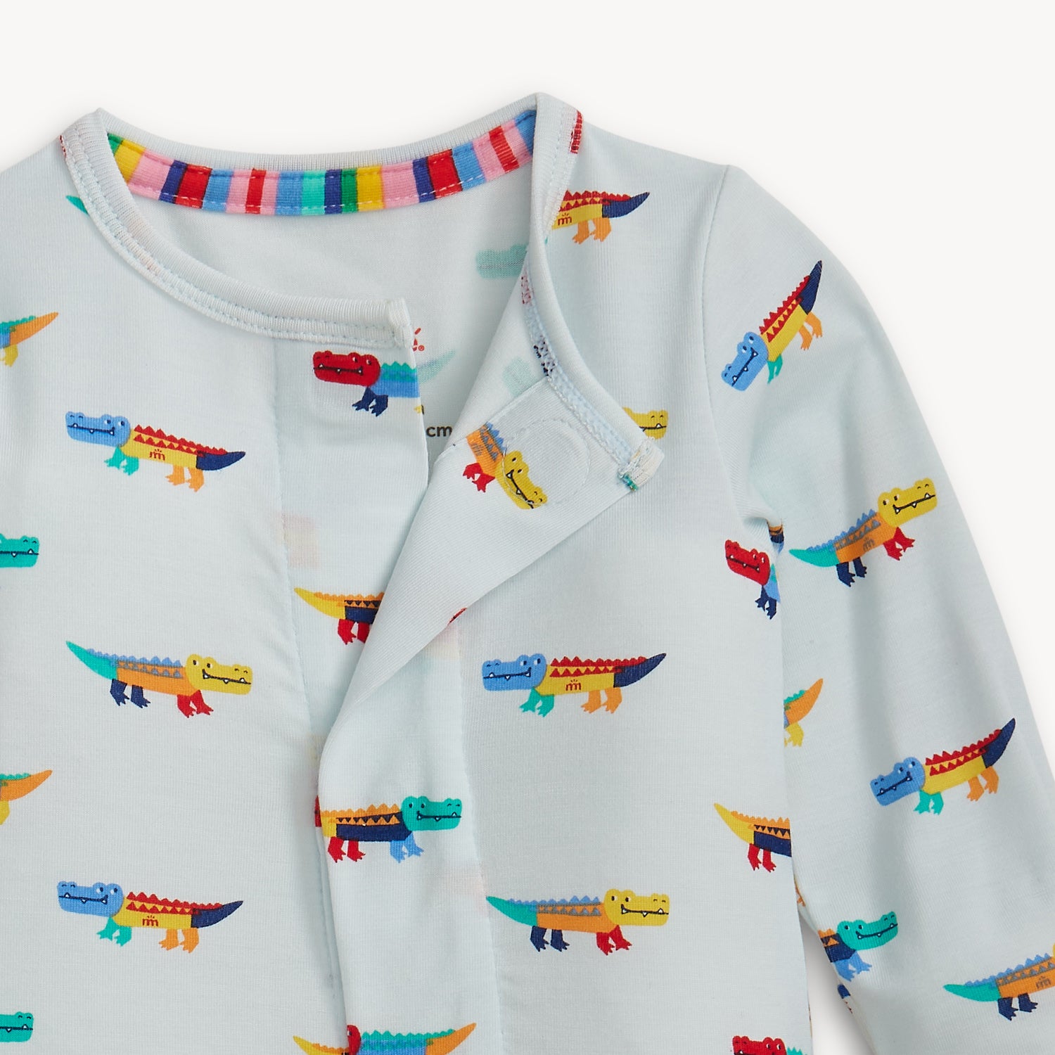 Open magnet in the front center of A long-sleeve footie in light blue featuring an all-over print of colorful, stylized crocodiles with a full-length magnetic closure, by Magnetic Me.