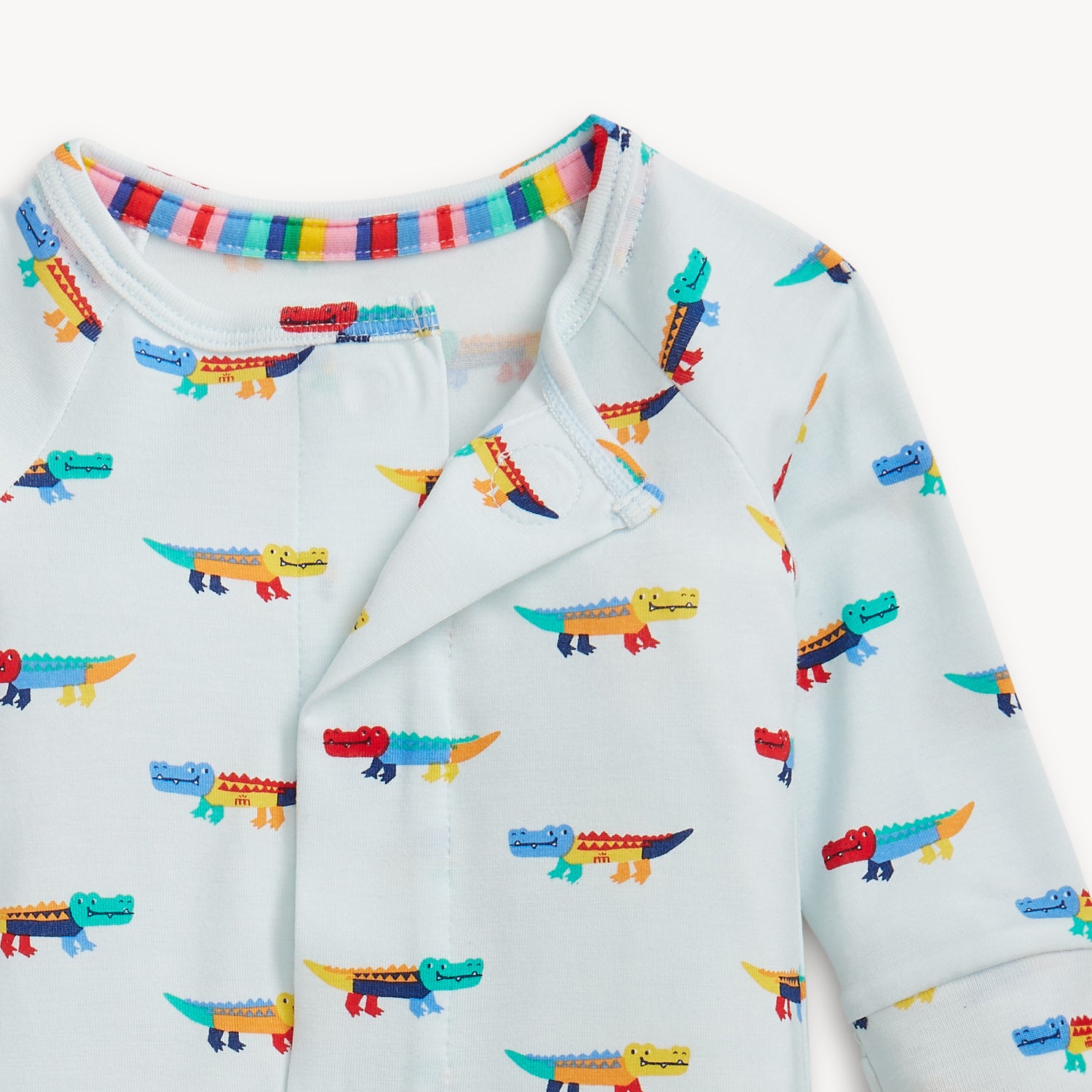 Open magnet in the center front of A long-sleeve convertible coverall in light blue featuring an all-over print of colorful, stylized crocodiles and ribbed cuffs, by Magnetic Me.