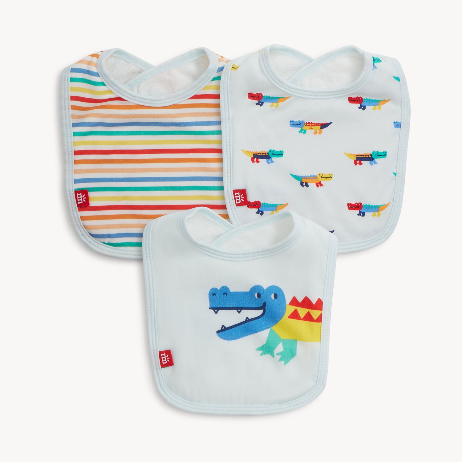 A pack of three baby bibs featuring a multi-color striped print on white, a colorful mini crocodile print on white, and a large crocodile graphic on light blue, all with magnetic shoulder closures, by Magnetic Me.