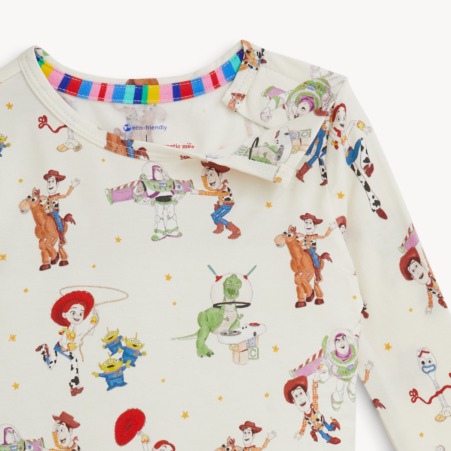Open magnet on the shoulder of A two-piece pajama set with a long-sleeve top and matching pants in a cream fabric featuring an all-over Disney Pixar Toy Story print of Woody, Buzz Lightyear, Jessie, Bullseye, Rex, Hamm, Slinky Dog, and the Aliens, by Magnetic Me.