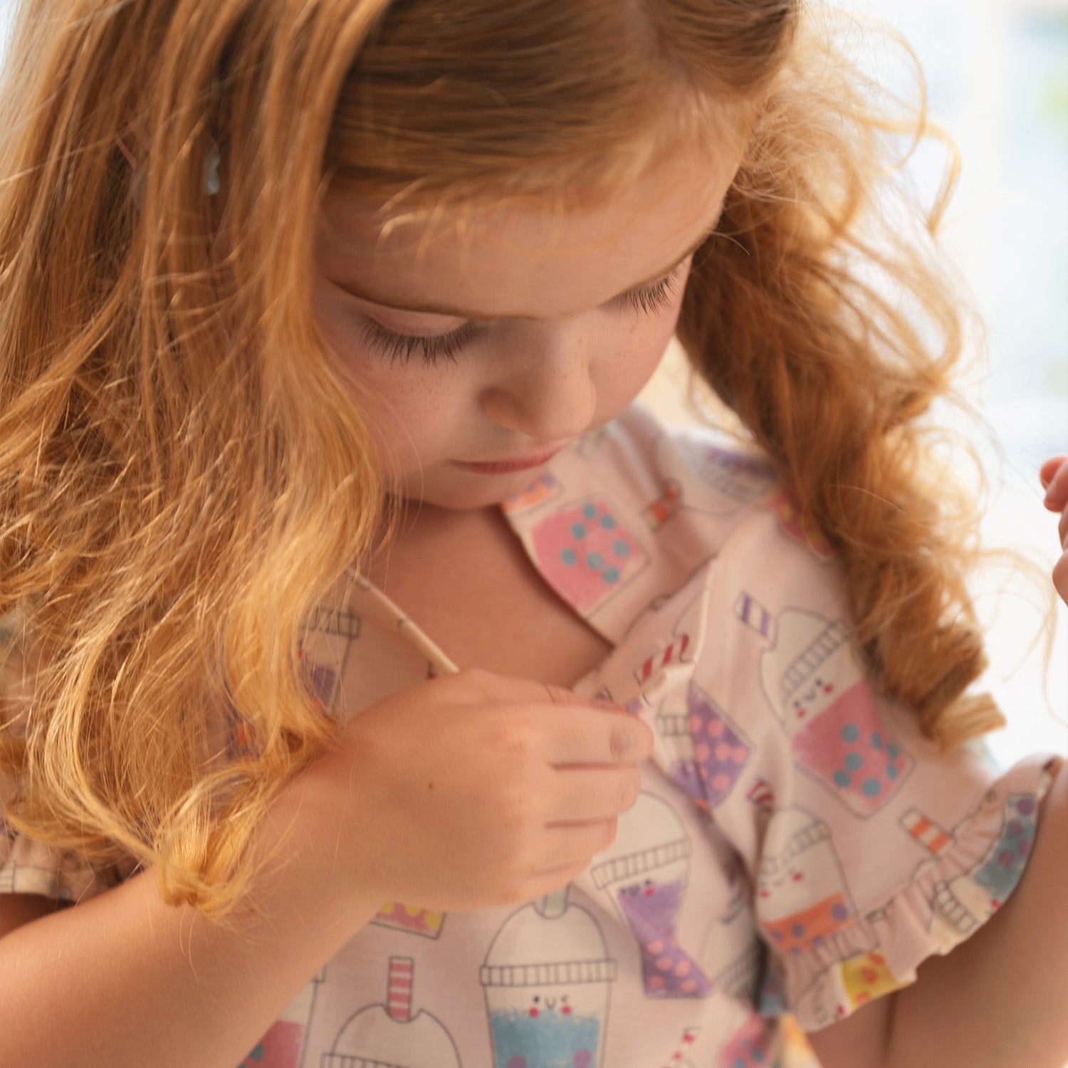 photo of a girl opening the magnet of A light pink short-sleeved nightgown with ruffled flutter sleeves and a hemmed ruffle, featuring a vibrant all-over print of smiling boba tea cups, by Magnetic Me.