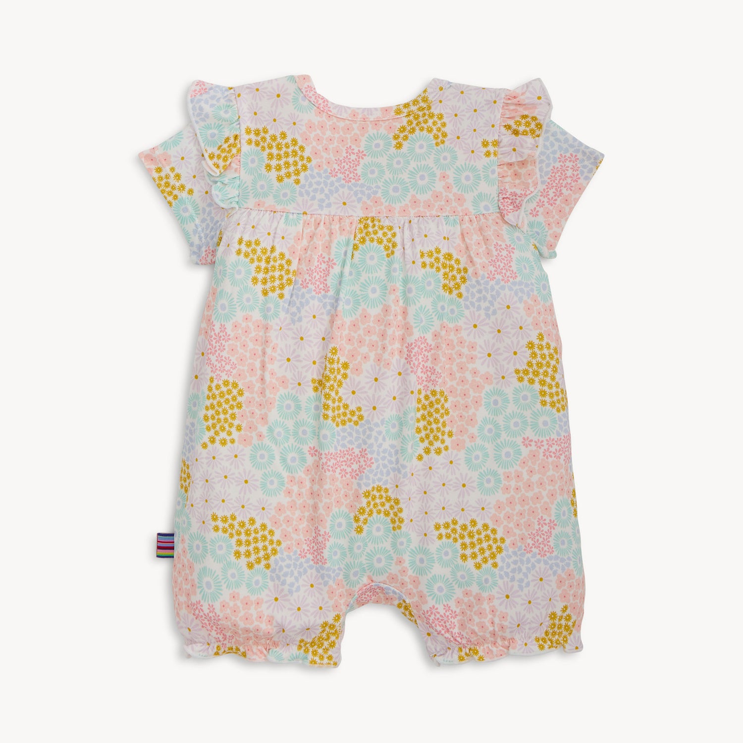 Back of A short-sleeve baby romper with ruffled shoulders and elastic leg openings featuring a dense pastel floral print of pink, yellow, and light blue wildflowers on a white background, by Magnetic Me.