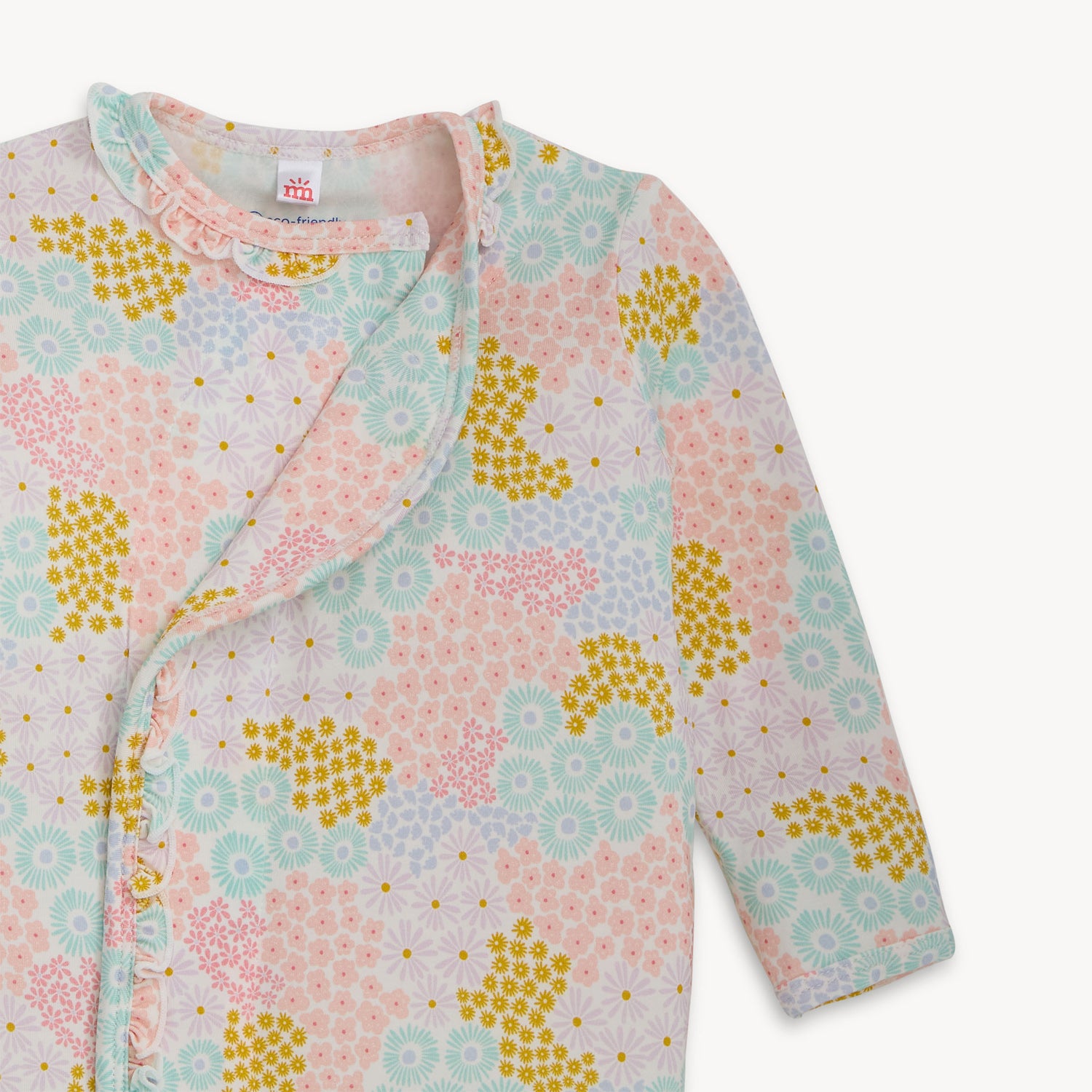 Open magnet on the front top of A long-sleeve infant sleeper gown and matching knotted hat with ruffle trim in a pastel meadow flower print, by Magnetic Me.